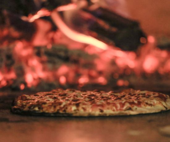 Wood Fired Pizza sitting in front of a running oven.